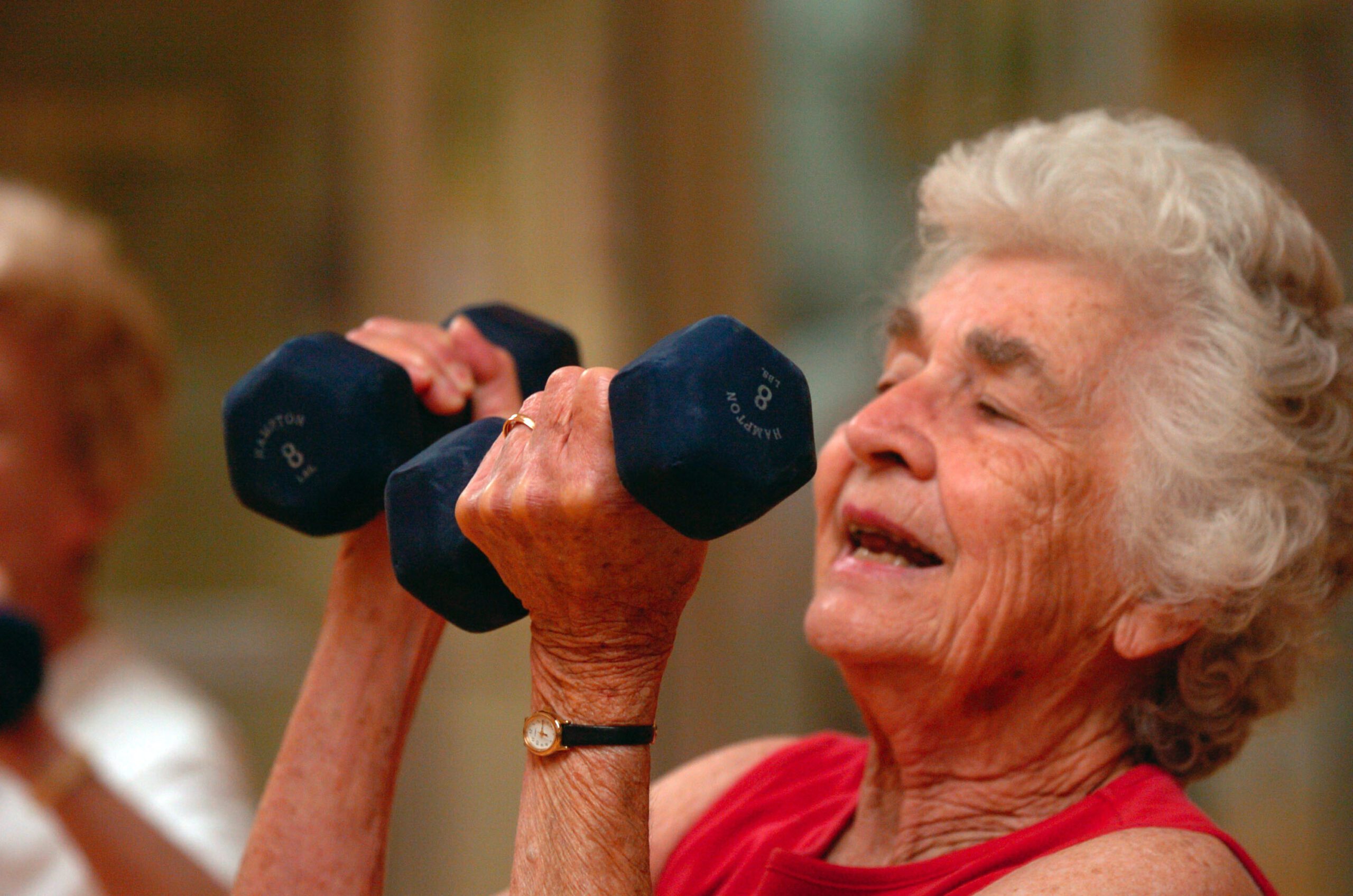 Older adult exercising with weights during an aerobics class — physical activity at any age supports brain volume and cognitive longevity.